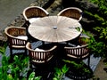 Round wooden patio table with chairs around in aerial view with green branches encroaching into the scene. Royalty Free Stock Photo