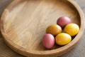 On a round wooden tray are five brightly colored Easter eggs and space for text.