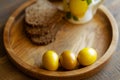 On a round wooden tray are three brightly colored Easter eggs and grain bread.