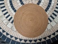 A round woven placemat on a tiled table surface