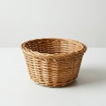 A round, woven wicker basket with a smooth texture sits on a white surface. The baske Royalty Free Stock Photo