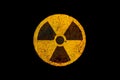 Round yellow and black radioactive ionizing radiation nuclear danger symbol on rusty metal grungy texture and isolated on black Royalty Free Stock Photo