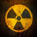 Round yellow radioactive ionizing radiation danger symbol painted on a massive rusty metal wall background