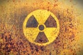 Round yellow radioactive ionizing radiation danger symbol painted on a massive rusty metal wall with rustic grunge texture