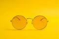 Round yellow tinted sunglasses on yellow