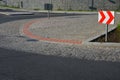 Roundabout of gray granite cubes closer to the center. beveled concrete curbs with flowers and grass in the middle of the circle.