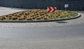 Roundabout of gray granite cubes closer to the center. beveled concrete curbs with flowers and grass in the middle of the circle.