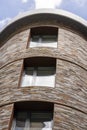 Rounded building, in stone, seen from below on its windows and its rounded facade.