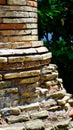 Rounded corner of ancient brick wall and stone scraps with a geometric pattern ruined by time,