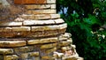 Rounded corner of ancient brick wall and stone scraps with a geometric pattern ruined by time,