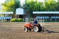 Route preparation at the racetrack - tractor aligns the ground. a rider on a horse rides nearby. equestrian sports