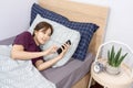 Daily routine concept a female teenager getting into the bed setting alarm in her smartphone before sleeping