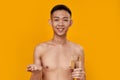 Daily Routine. Portrait Of Shirtless Young Asian Man Smiling At Camera, Holding Pills And Glass Of Water Isolated Over