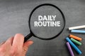 Daily Routine. Text and magnifying glass on a dark chalkboard Royalty Free Stock Photo