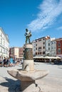 ROVINJ, CROATIA-AUGUST 30, 2018: Tourists walk by the Fountain with a sculpture of a boy and a fish and a clock Tower on Royalty Free Stock Photo