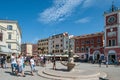 ROVINJ, CROATIA-AUGUST 30, 2018: Tourists walk by the Fountain with a sculpture of a boy and a fish and a clock Tower on Royalty Free Stock Photo