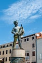 ROVINJ, CROATIA-AUGUST 30, 2018: Tourists walk by the Fountain with a sculpture of a boy and a fish and a clock Tower on Royalty Free Stock Photo