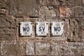 Row of ancient old English Victorian iron fire hydrant sign plaques on stone granite wall black and white. Symmetrical row steel