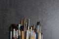 Row of artist paint brushes of various models closeup on a dark decorative stucco surface with a copy space. Royalty Free Stock Photo