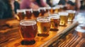 A row of assorted beers in a tasting flight, displayed on a wooden table at a bustling brewery. Royalty Free Stock Photo