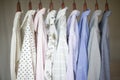 A row of assorted business shirts for women on hangers in a closet