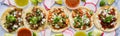 Row of assorted mexican street tacos with garnishes in wide banner composition Royalty Free Stock Photo