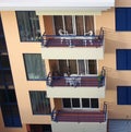 Ow of balconies with tables and chairs in an orange and blue concrete apartment building