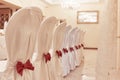 A row of banquet chairs with white covers and red ribbon bows Royalty Free Stock Photo