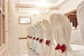 A row of banquet chairs with white covers and red ribbon bows Royalty Free Stock Photo