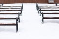 A row of benches covered with snow. Top view. Wooden and steel benches in the park Royalty Free Stock Photo