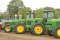 A row of big green tractors at a big farm event outdoors