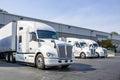 Row of the big rig semi trucks tractors with dry van semi trailers standing in warehouse docks loading cargo for the next delivery Royalty Free Stock Photo