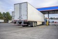 Row of the big rigs semi trucks with semi trailers filling tanks with diesel fuel standing on the fuel station on truck stop Royalty Free Stock Photo