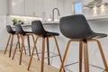 Row of black brown stools near a kitchen island in a residential modern home