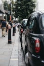 Row of Black cabs parked on a side of the road in City of London, London, UK.