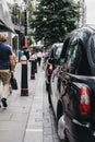 Row of Black cabs parked on a side of the road in City of London, London, UK. Royalty Free Stock Photo