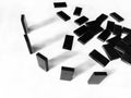 A row of black dominoes on a white background. There are many black domino stones stacked nearby. Royalty Free Stock Photo