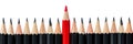 Row of black pencils with one red pencil in middle Royalty Free Stock Photo