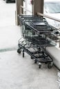 Row of black shopping cart with black handle lined up on cement Royalty Free Stock Photo