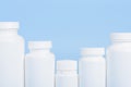 Row of blank white plastic bottles of medicine pills or supplements