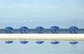 Row of blue beach umbrellas and chairs Royalty Free Stock Photo