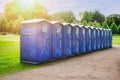 Row of Blue Portable Toilets in Park