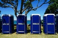 A row of blue toilet cubicles at an outdoor event