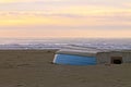 Row boat upside down on a winter shore at sunset