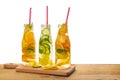 row of bottles lemonade with lemon, orange, lime, twig mint, cucumber, ginger and straws on wooden background isolated, concept o Royalty Free Stock Photo