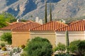 Row of box design houses with gable style roofs with adobe red roof tiles and desert beige and orange exterior stucco