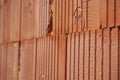 Row of bricks in red color with the inner holes in the shape of honeycomb on the construction site