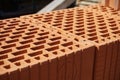 Row of bricks in red color with the inner holes in the shape of honeycomb on the construction site