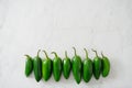 A row of bright green jalapeno peppers on a white marble background with copy space Royalty Free Stock Photo