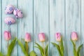 Row of bright pink tulips on blue wooden background and colored easter eggs, top view Royalty Free Stock Photo